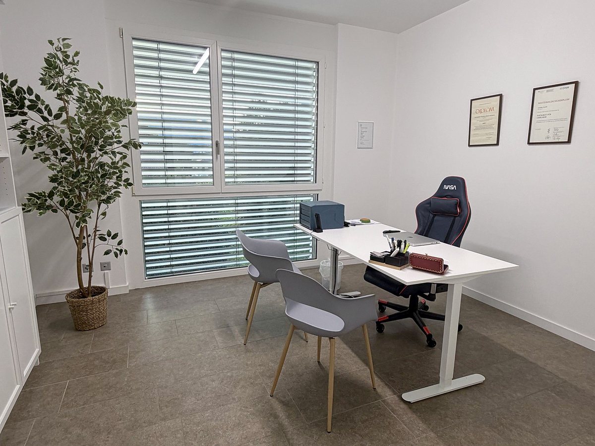The consultation room with the desk and the two chairs by the window